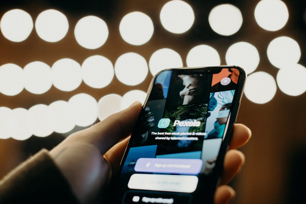 person holding black phone with bokeh photography background