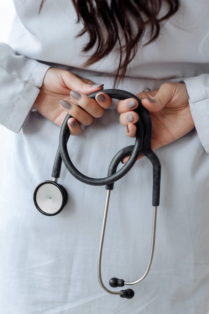 hands with gray nail polish on her fingers while holding stethoscope
